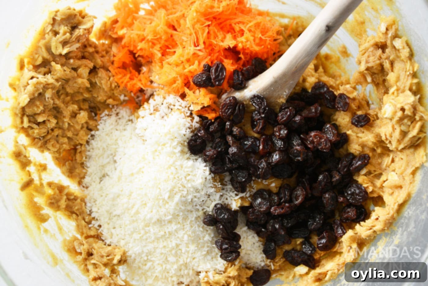 stirring in carrots, shredded coconut, and raisins to a bowl of cookie dough