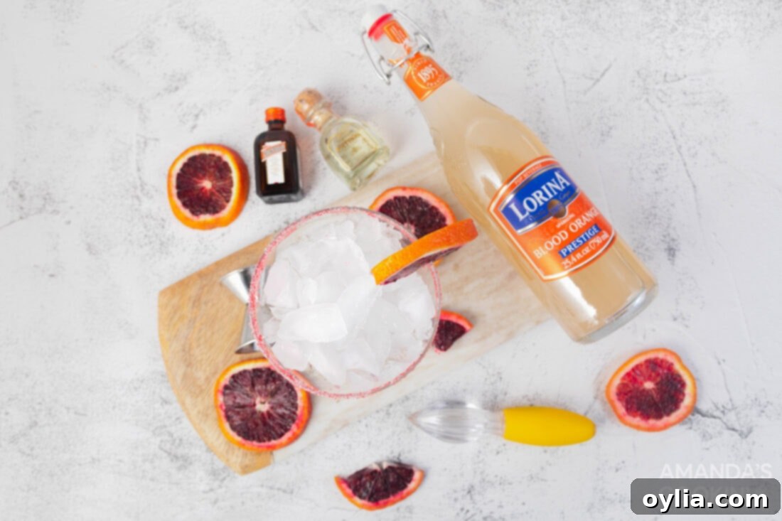 Ingredients laid out for making a blood orange margarita, including tequila, orange liqueur, and blood oranges.
