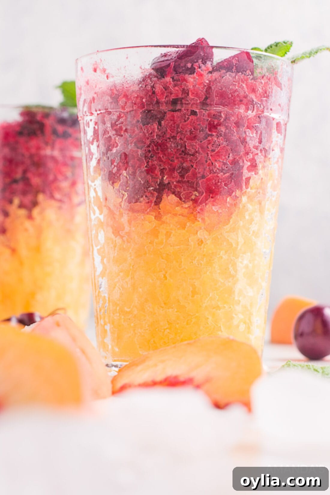 cherry and peach slushies layered in drinking glasses