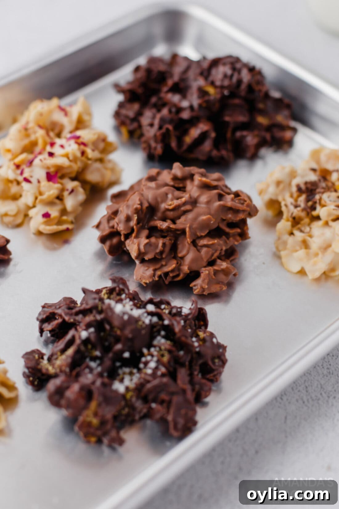Crispy no-bake chocolate cornflake cookies scattered on a parchment-lined baking sheet, showcasing their rich texture.