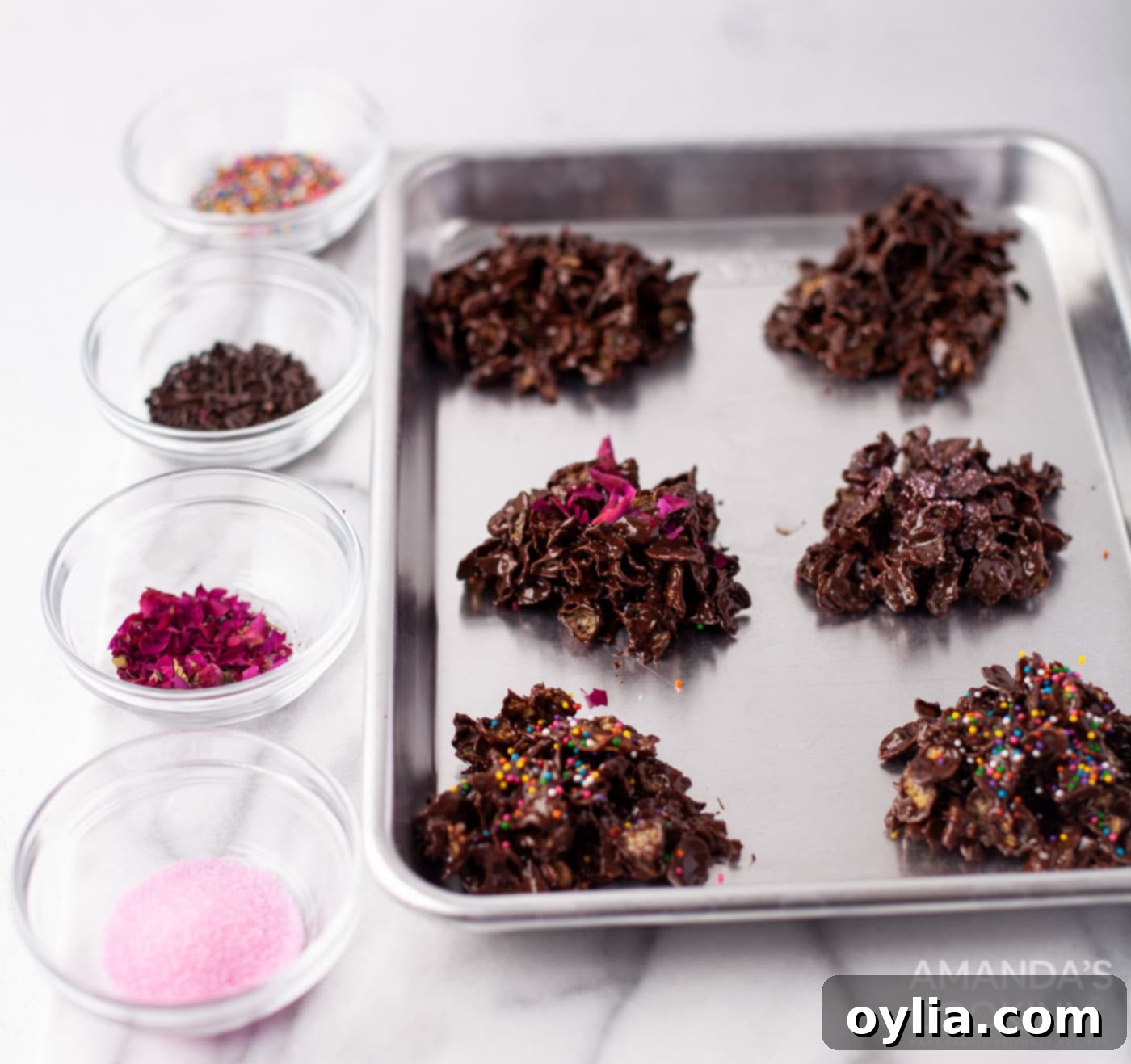 Sprinkling colorful sprinkles and sea salt onto freshly scooped chocolate cornflake cookies before chilling.