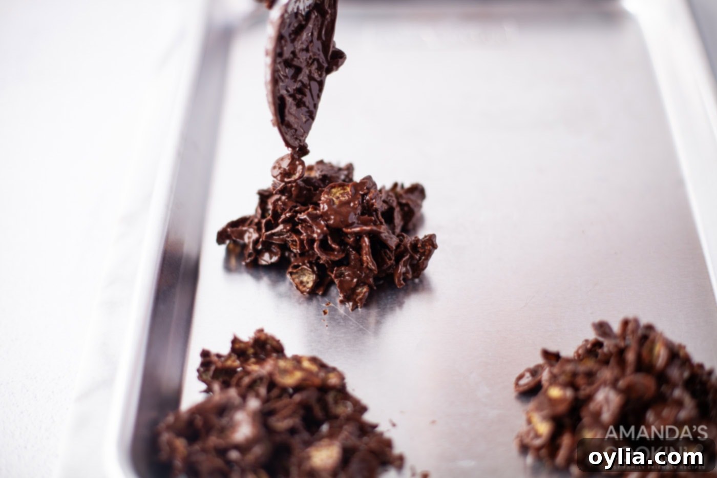 Dark chocolate cornflake cookies being scooped onto a baking sheet, showing their rich color.