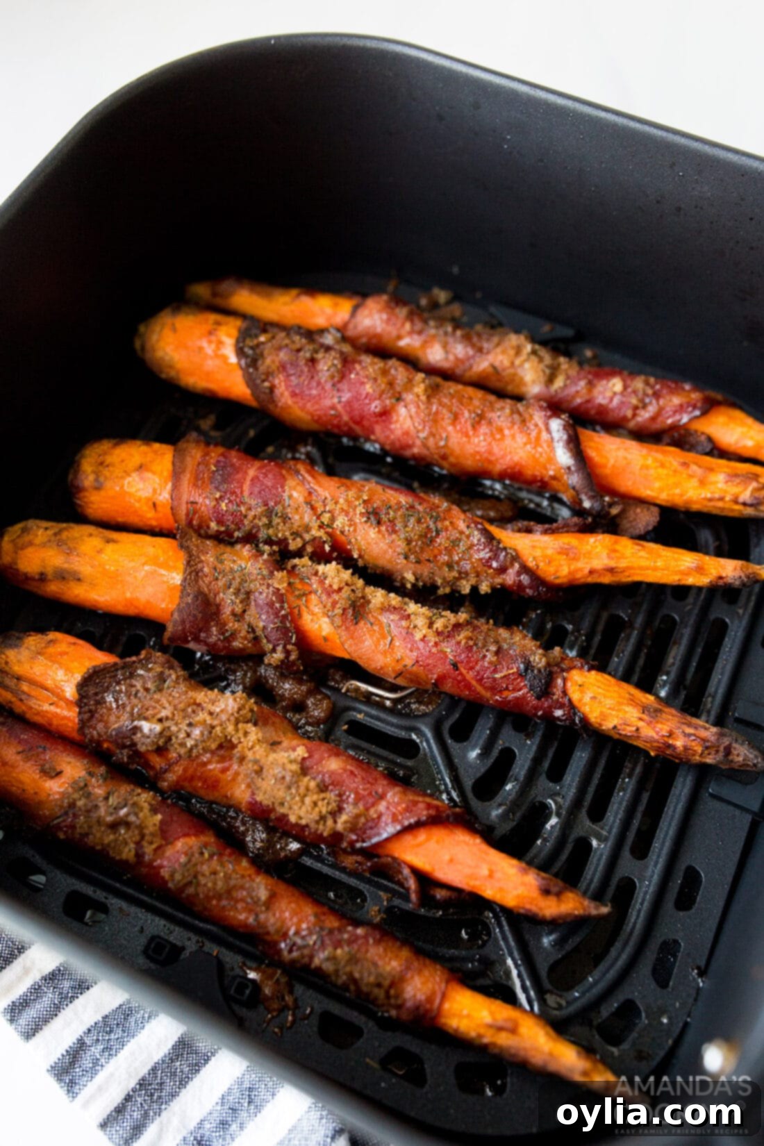 Sweet and Savory Air Fryer Bacon Wrapped Carrots 3 bacon wrapped carrots in the air fryer basket