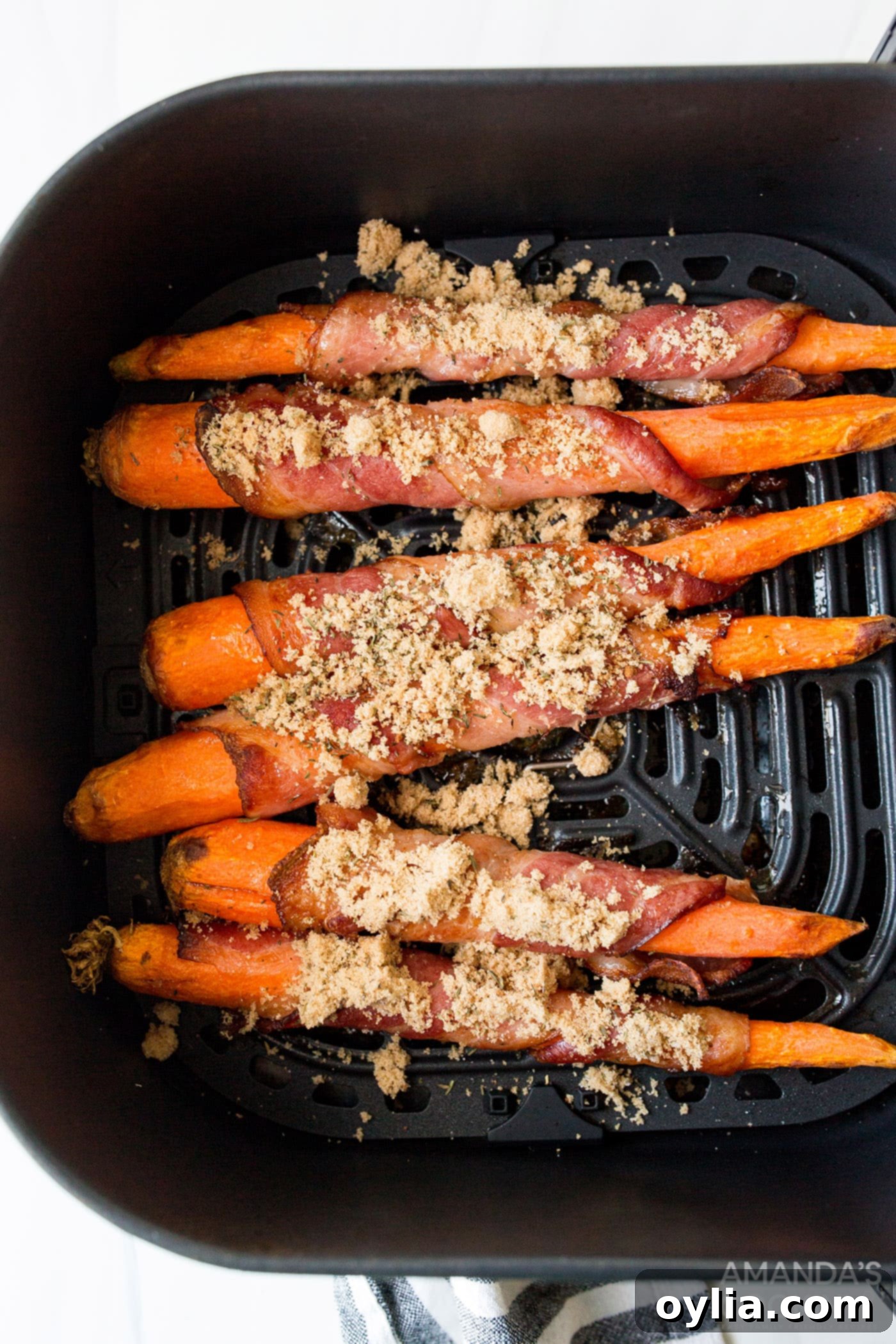 Sweet and Savory Air Fryer Bacon Wrapped Carrots 7 brown sugar sprinkled on bacon wrapped carrots in an air fryer