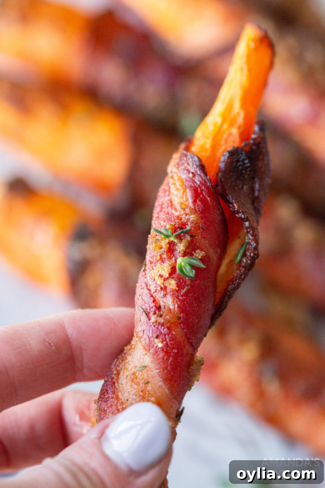 Sweet and Savory Air Fryer Bacon Wrapped Carrots 9 holding a bacon wrapped carrot