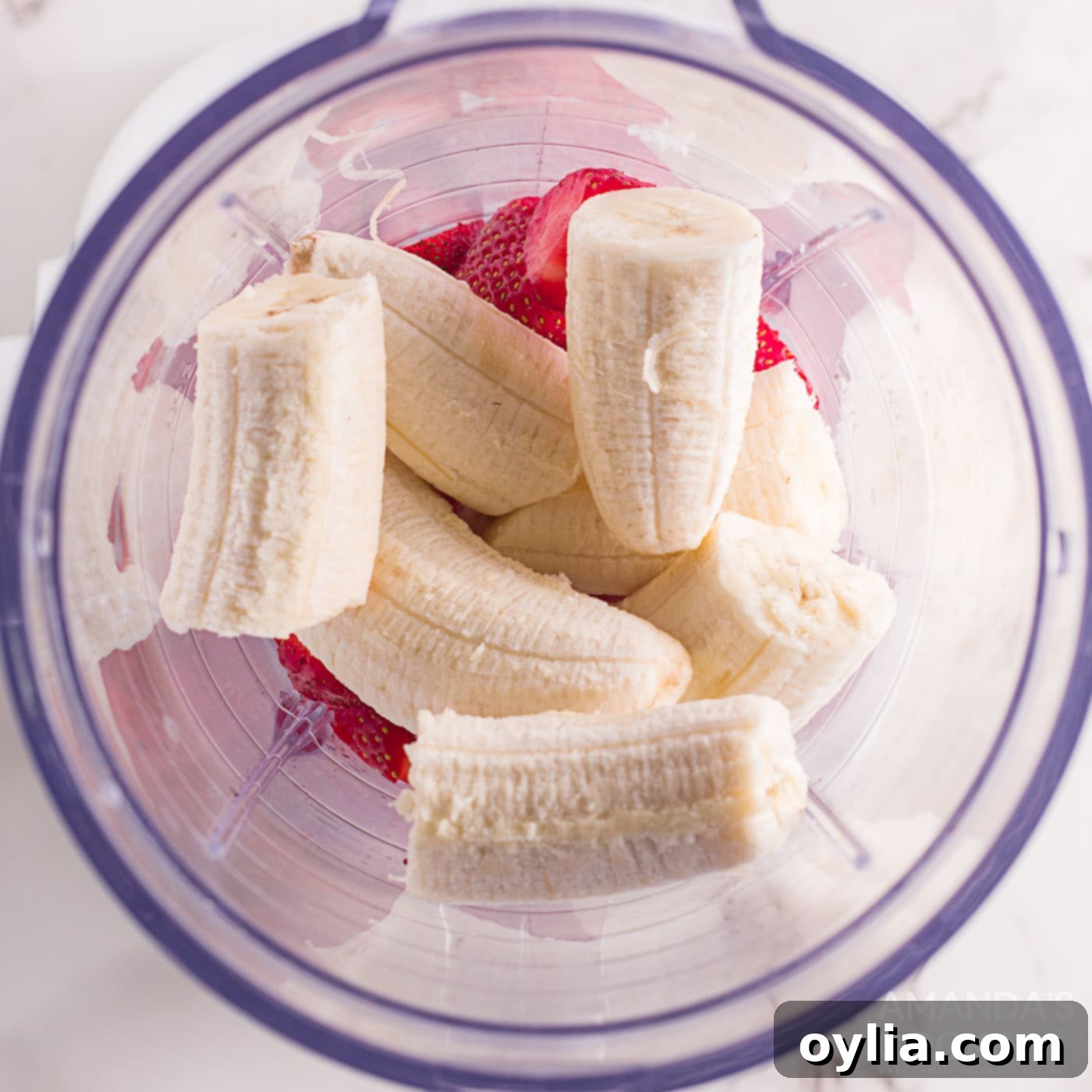 bananas added to strawberries in a blender, ready for blending