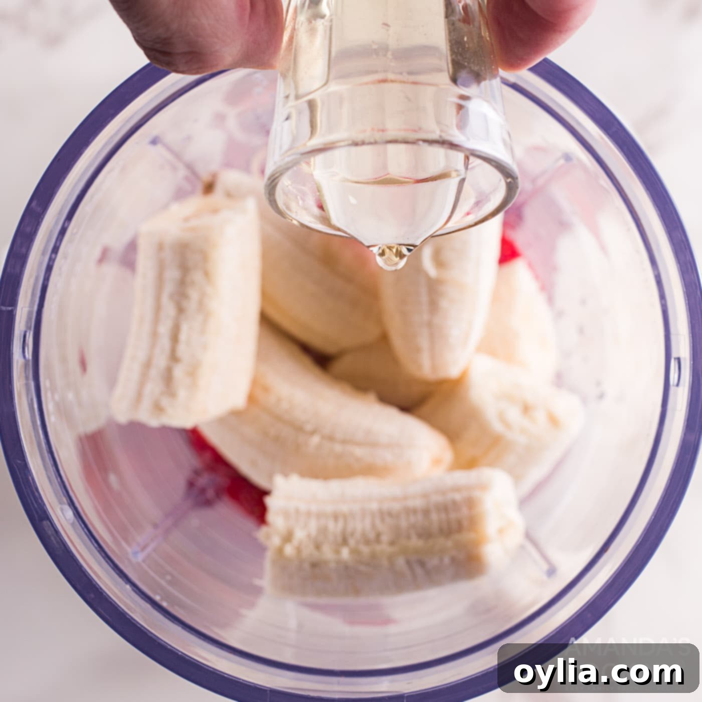 adding simple syrup to bananas and strawberries in blender
