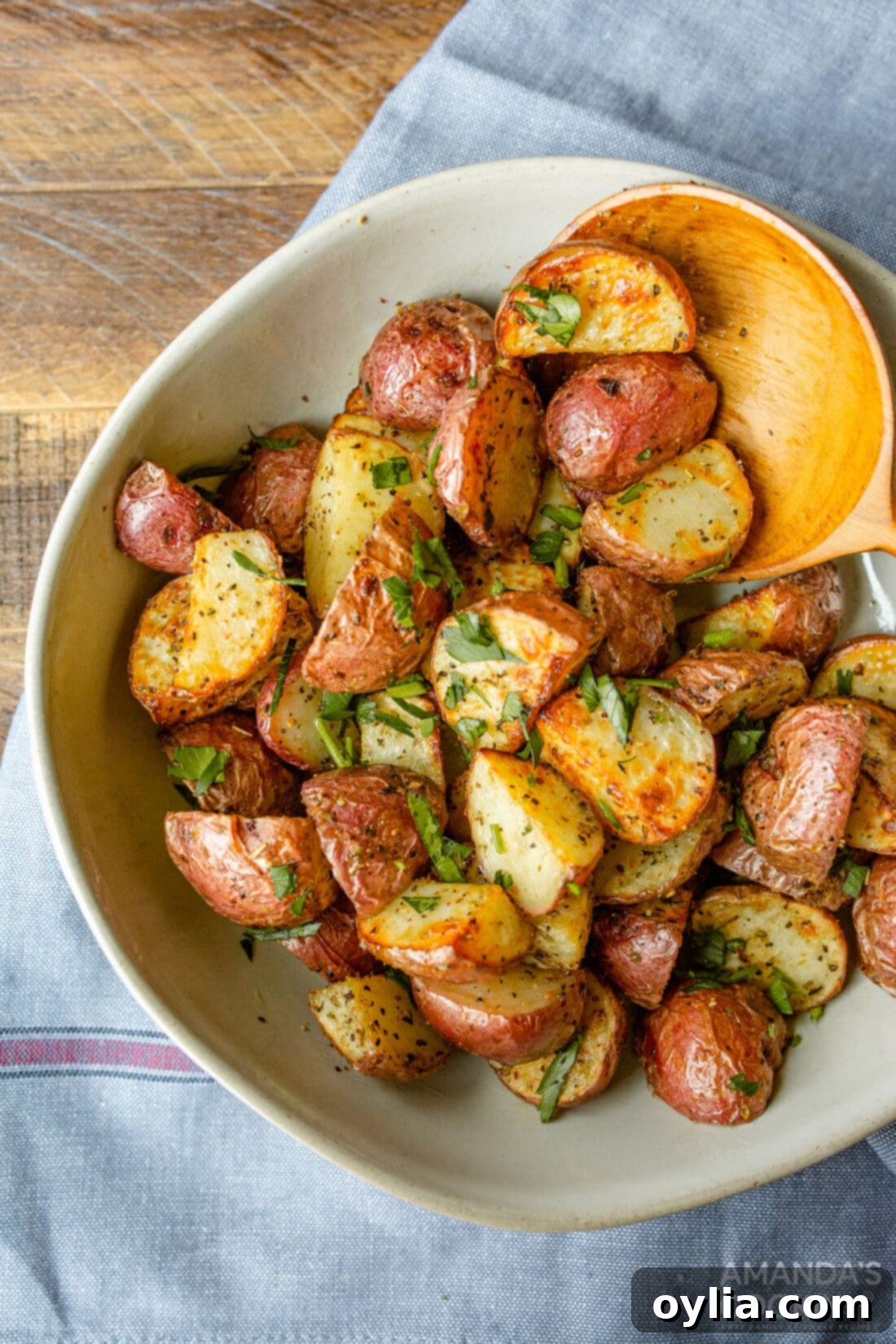A bowl filled with perfectly roasted, crispy air fryer potatoes, garnished with fresh herbs.