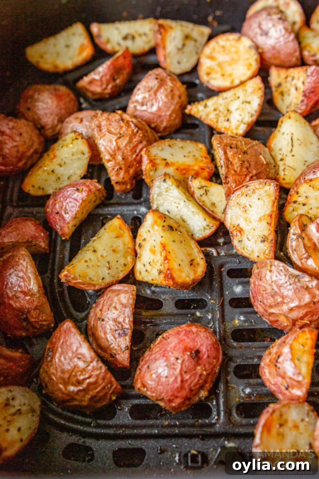 Close-up of perfectly golden-brown roasted potatoes inside an air fryer basket, showing their crispy texture.