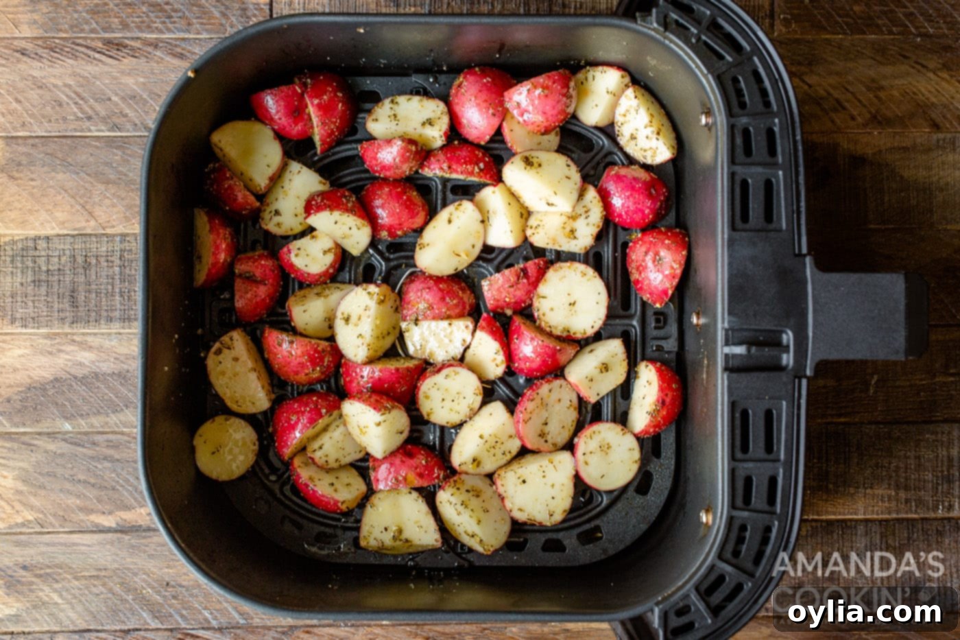Raw, seasoned potato cubes neatly arranged in a single layer inside an air fryer basket, ready for cooking.