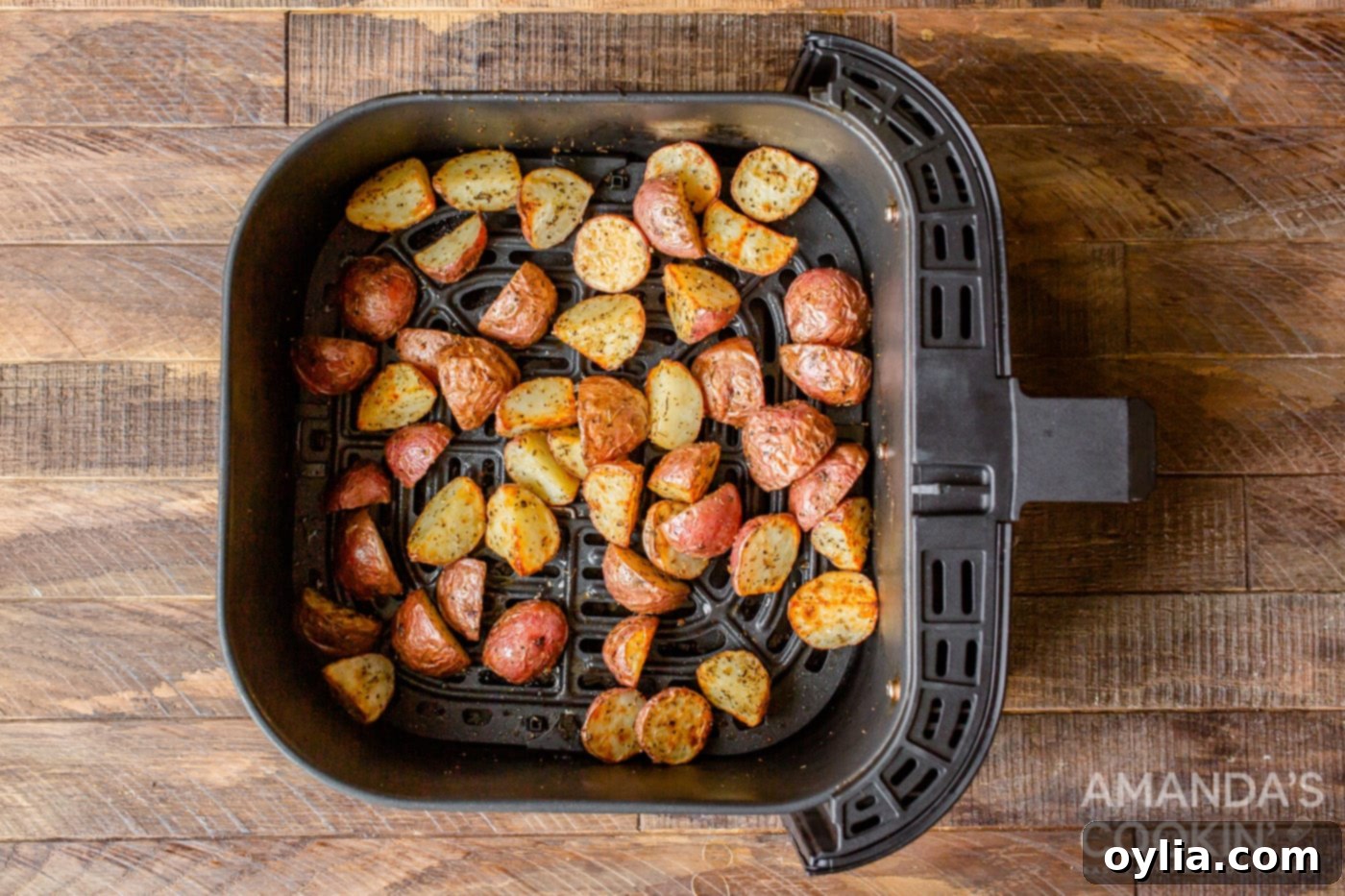 Cooked, golden-brown crispy roasted potatoes fresh out of the air fryer, ready to be served.