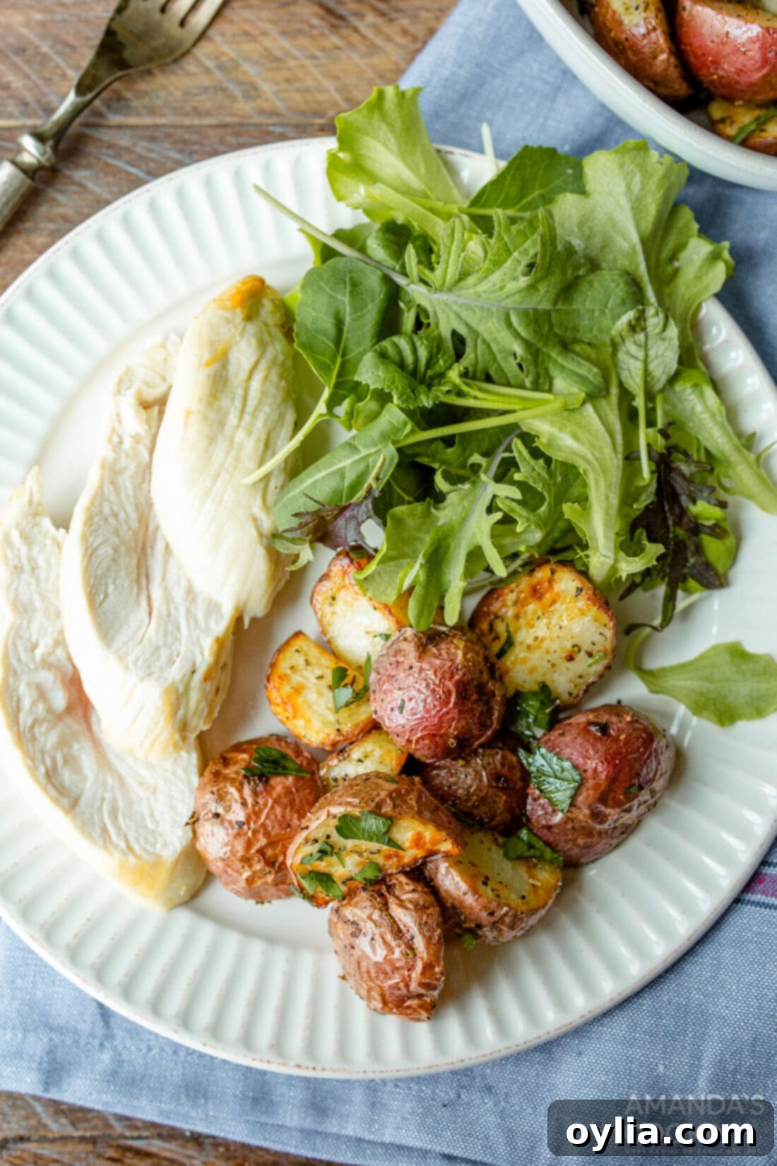 A plate featuring air fryer roasted potatoes, grilled chicken, and fresh salad greens, showcasing a complete meal.