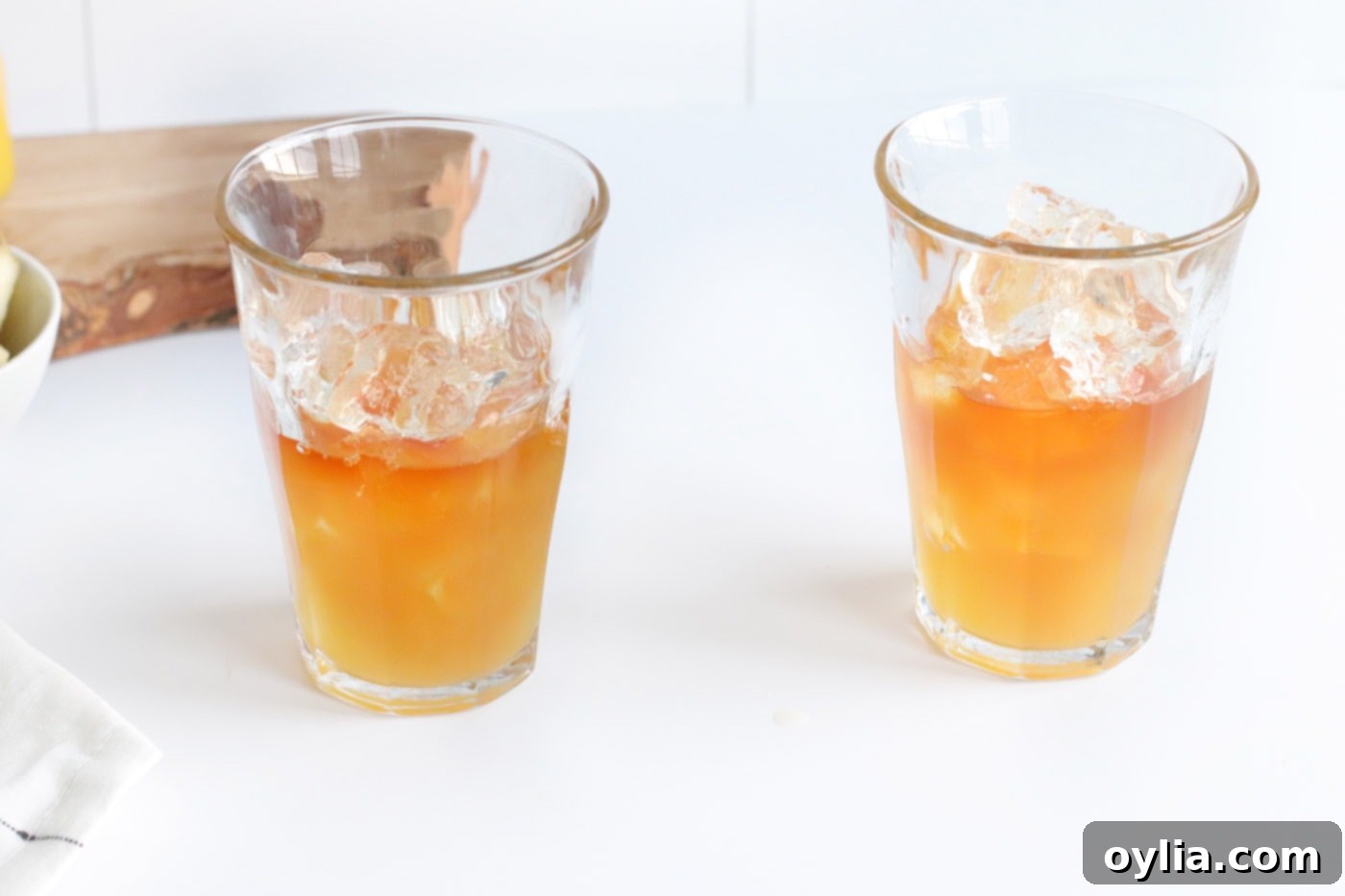 Pineapple juice being poured into a glass with rum and ice