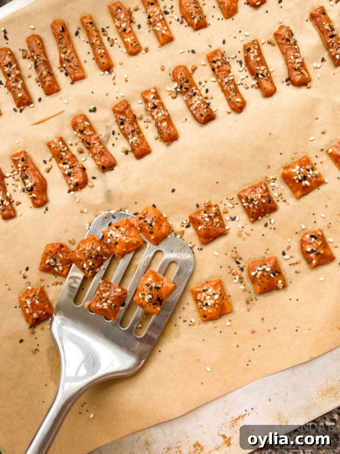 spatula carefully lifting golden keto cheese crackers from a baking sheet