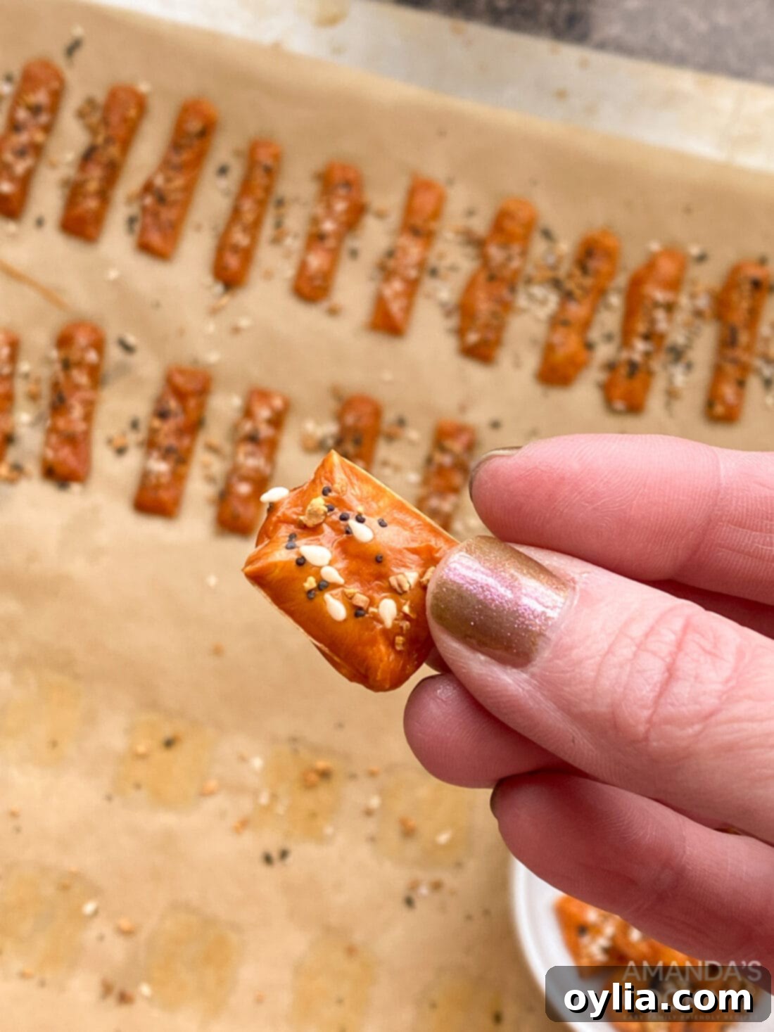 hand holding a perfectly crispy keto cheese cracker with a bowl in the background
