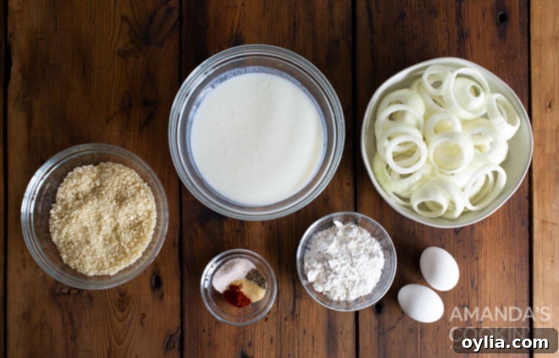 Ingredients laid out for Air Fryer Onion Rings including onion, buttermilk, panko, flour, eggs, and seasonings