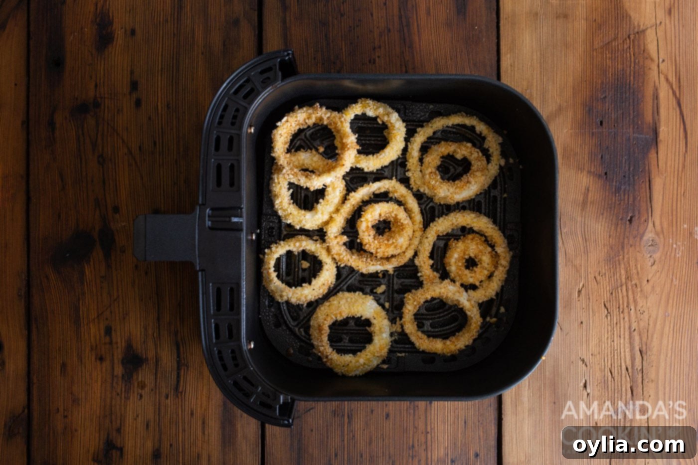 Breaded onion rings placed in an air fryer basket, ready for cooking