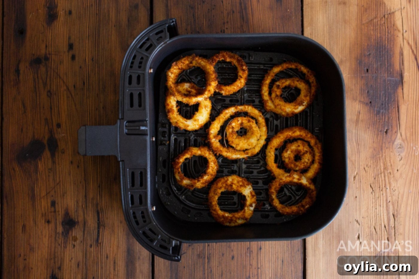 Golden brown air fried onion rings cooking in an air fryer basket