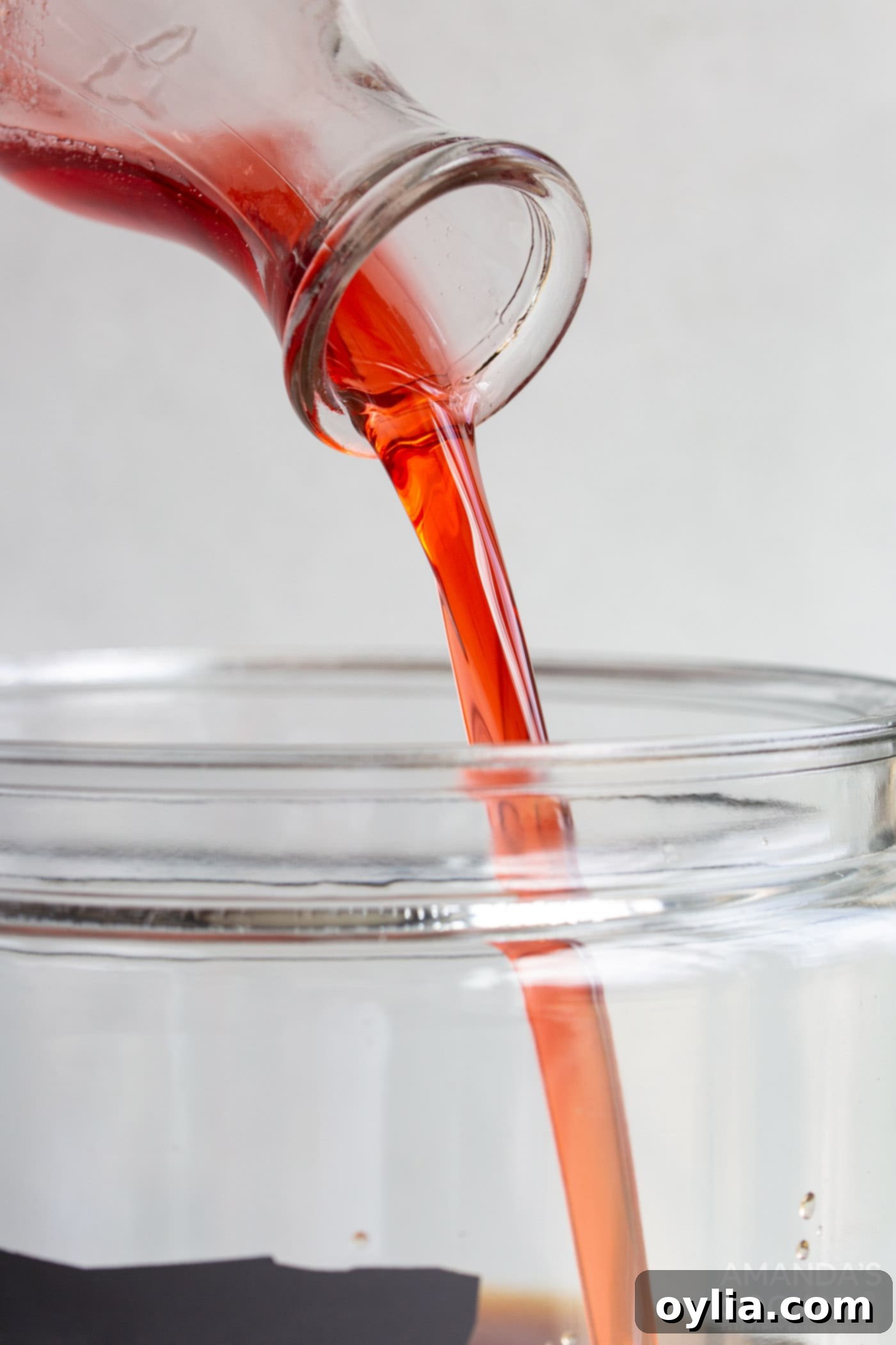 pouring strawberry simple syrup in a pitcher