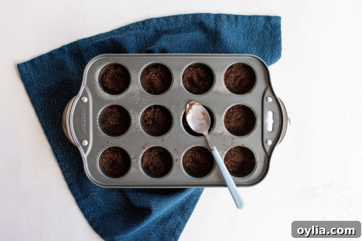spoon in graham cracker crust into mini muffin pan