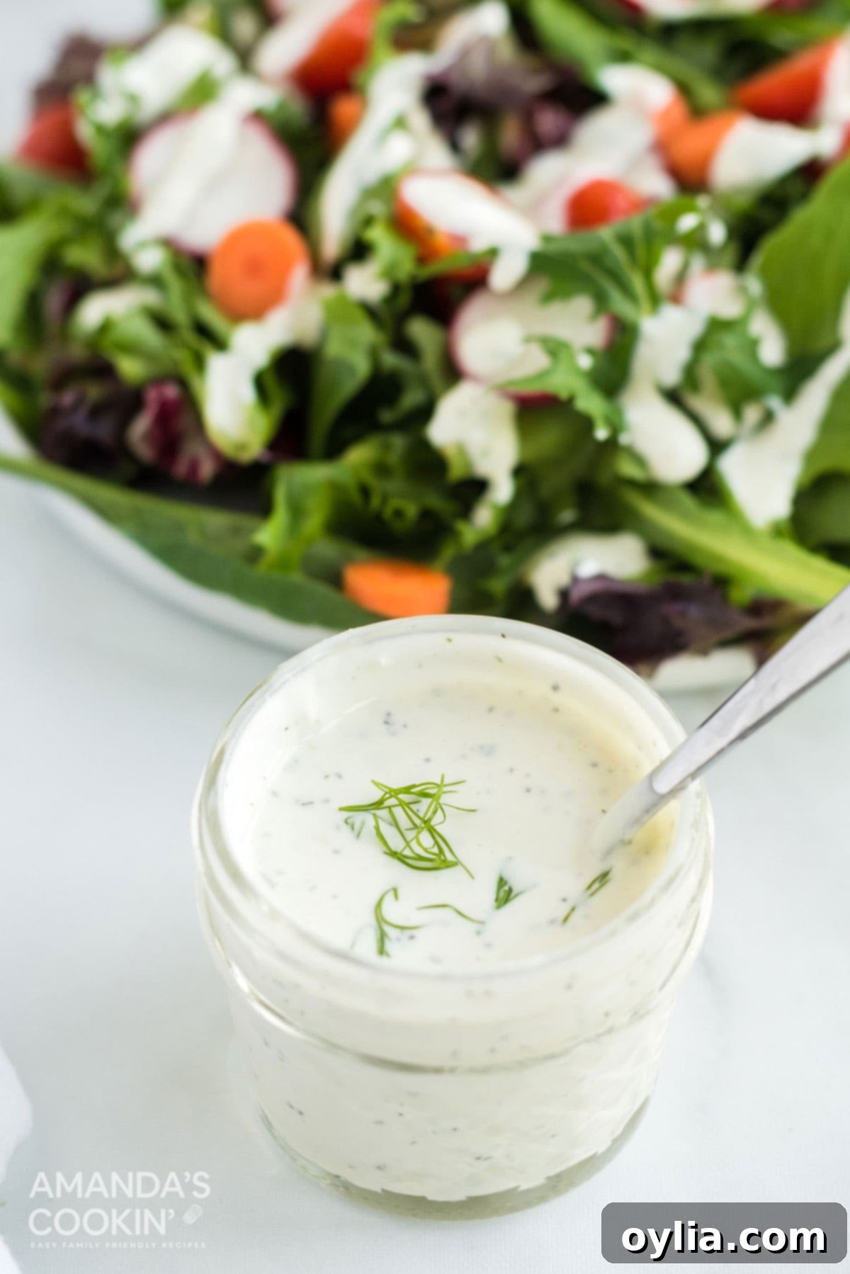 2 minutes and 7 ingredients is all it takes to make a delicious homemade dill dressing that also doubles as a vegetable dip! jelly jar of dill dressing with salad behind it