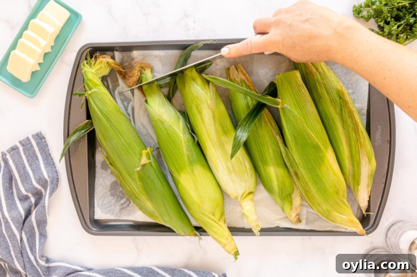 corn drying on a baking sheet with paper towels before grilling