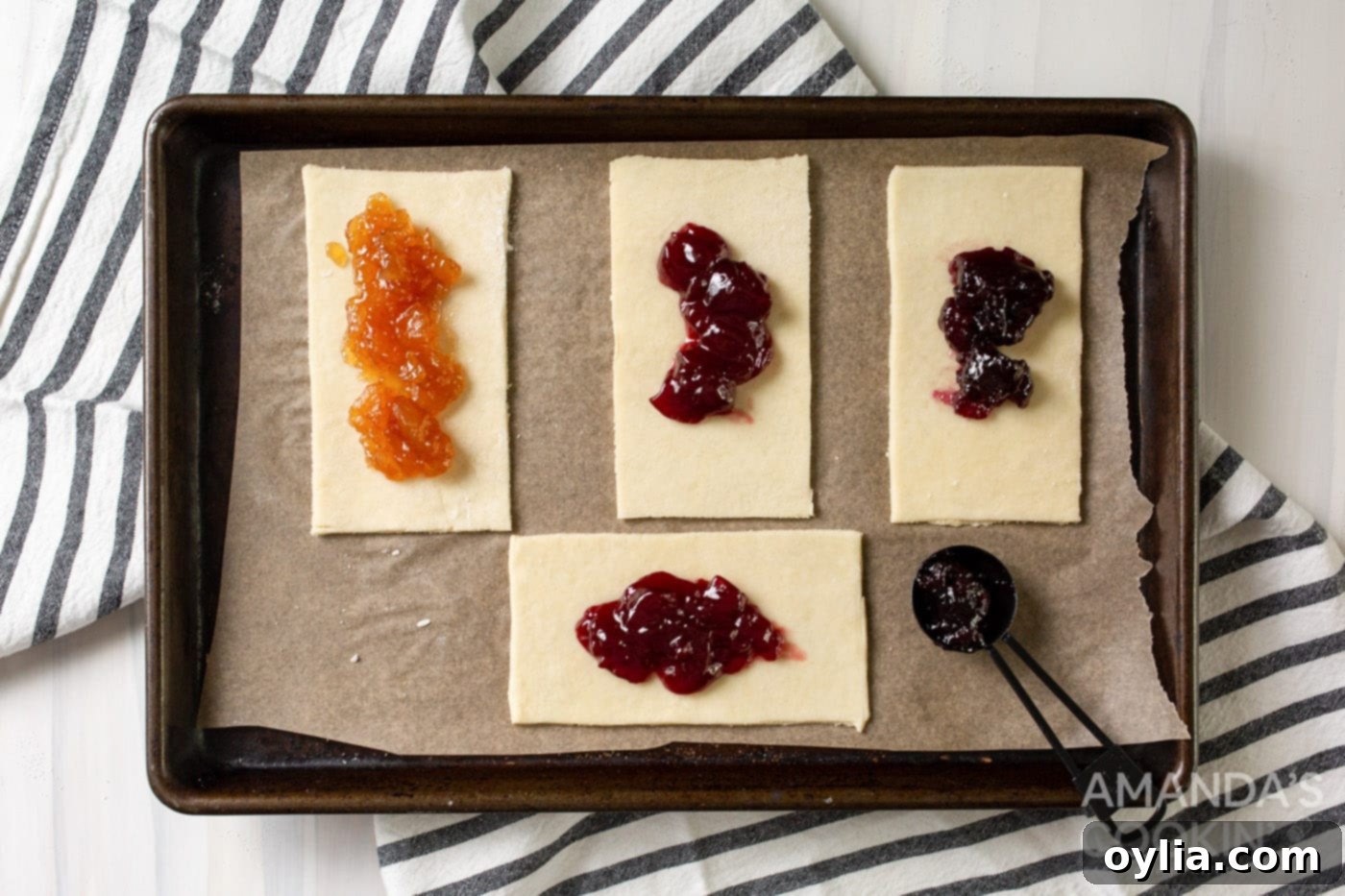Pie dough rectangles on a baking sheet, with sweet jam spread in the center