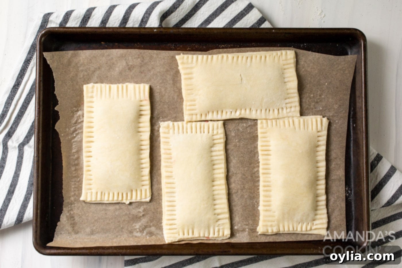 Unbaked pop tarts with crimped edges placed on a baking sheet