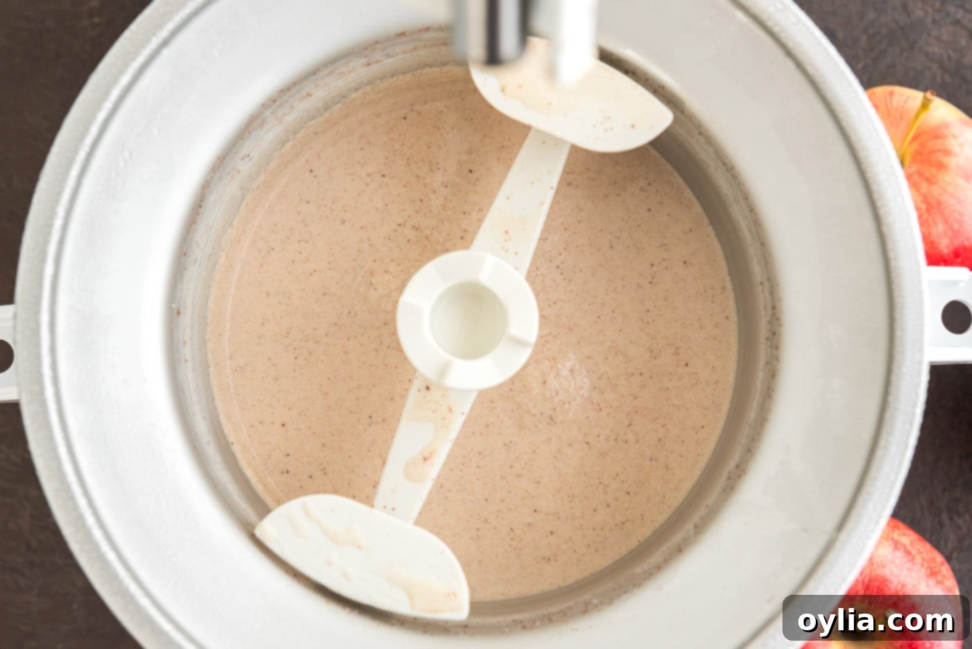 The apple cider ice cream mixture churning in an ice cream maker, gradually thickening.