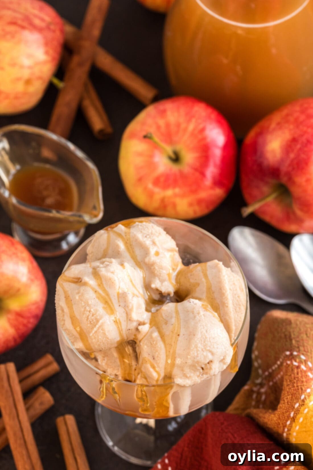 Multiple scoops of Apple Cider Ice Cream nestled in a clear dish, generously topped with a warm caramel drizzle.