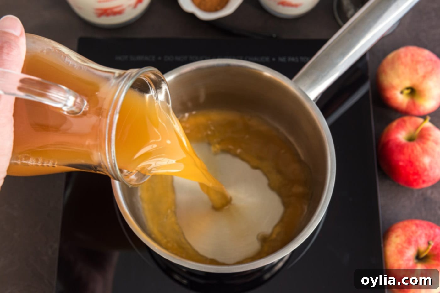 Pouring fresh apple cider into a saucepan to begin the reduction process.