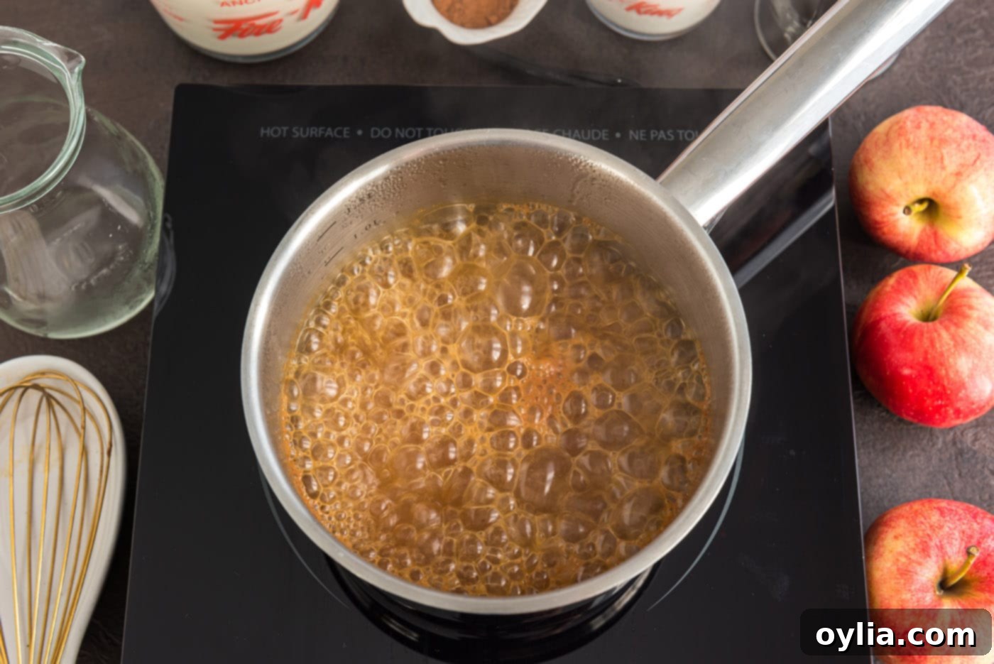 Apple cider vigorously boiling in a saucepan, actively reducing to concentrate its flavor.