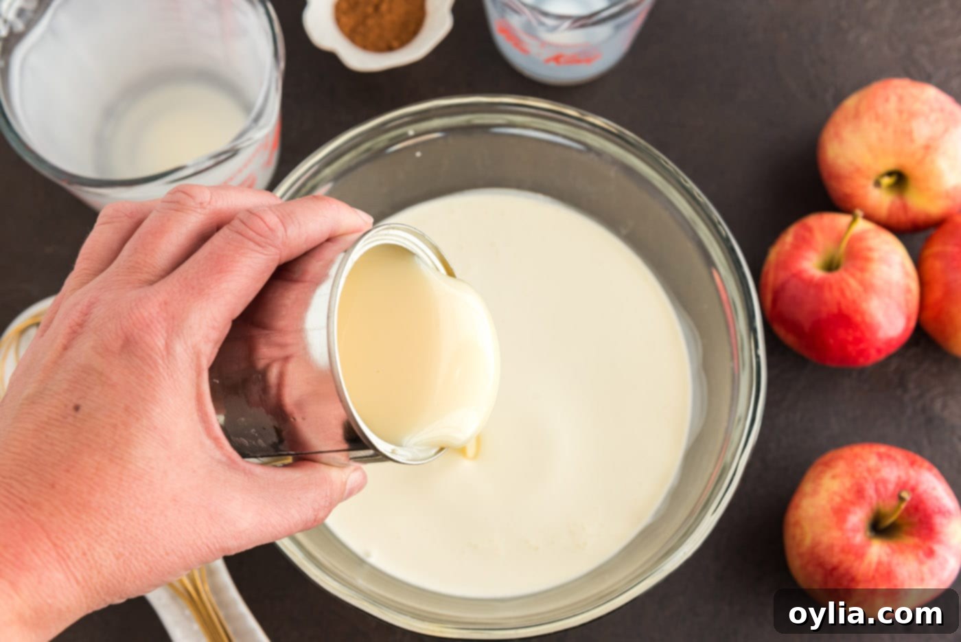 Sweetened condensed milk being added to the heavy cream in a bowl for the ice cream mixture.