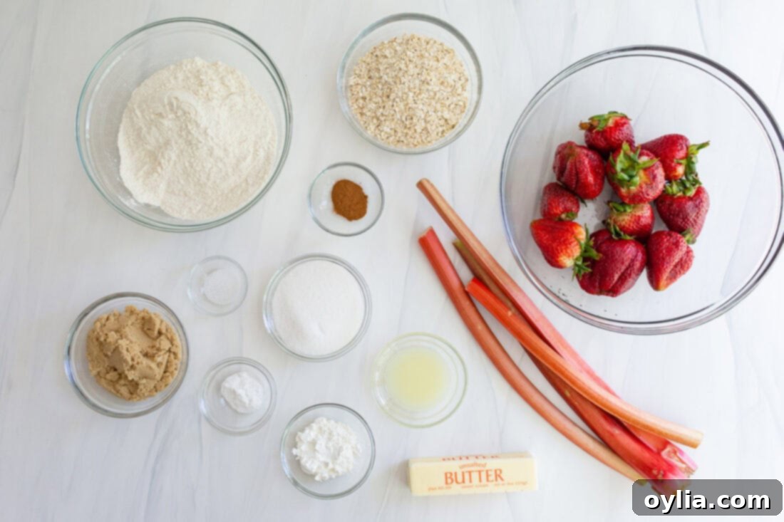 Ingredients for Strawberry Rhubarb Crumble Bars laid out on a table, including strawberries, rhubarb, flour, oats, sugar, and butter.