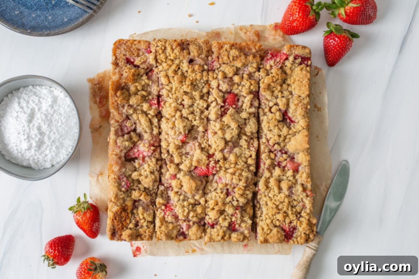 Sliced strawberry rhubarb crumble bars arranged on a cutting board.