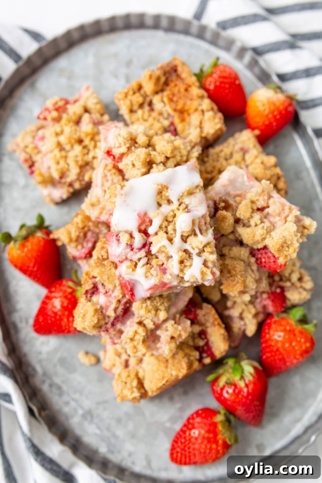 Strawberry Rhubarb Crumble Bars piled high on a white serving platter, ready to be enjoyed.