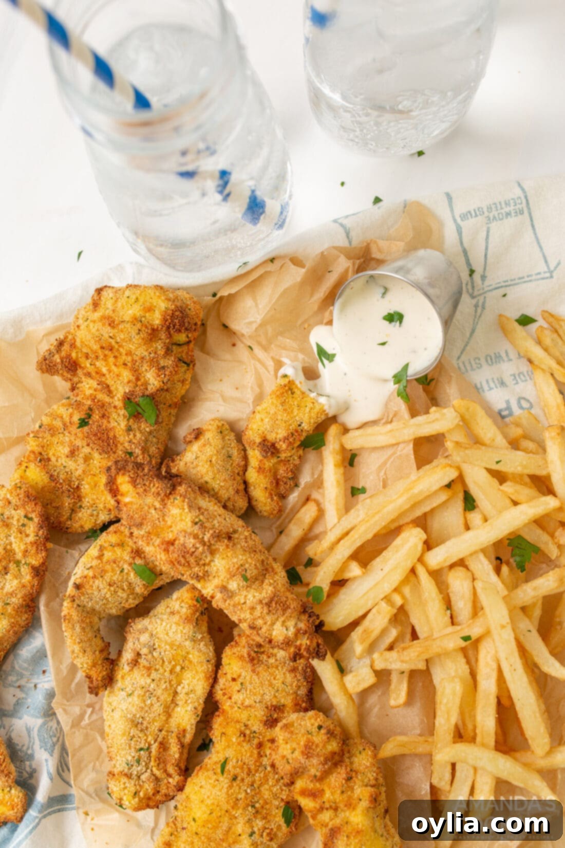 Quick and Crispy Air Fryer Chicken Tenders 3 air fryer chicken tenders with fries on parchment