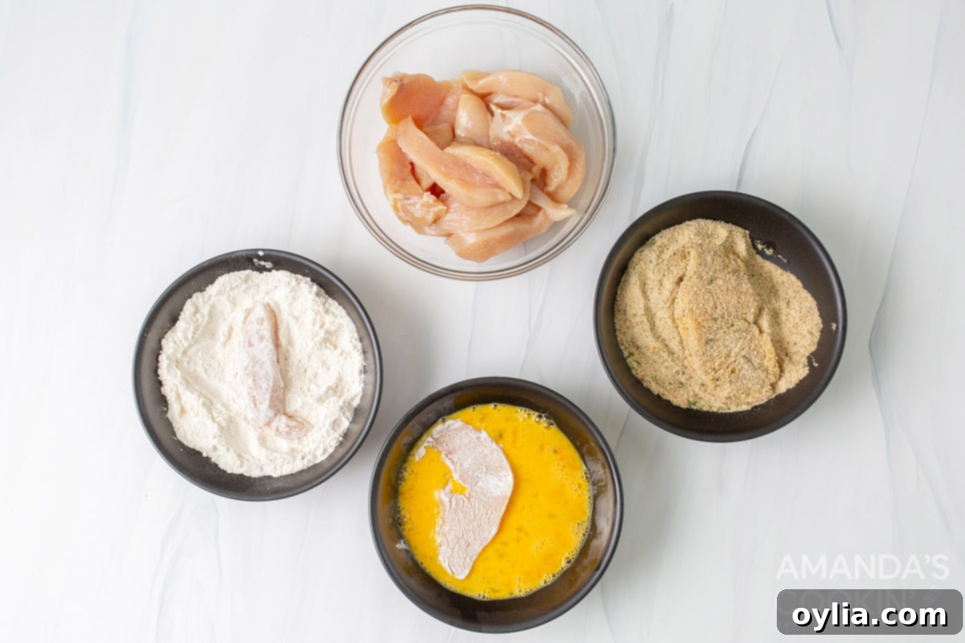 flour, eggs,, breadcrumbs, and chicken in bowls