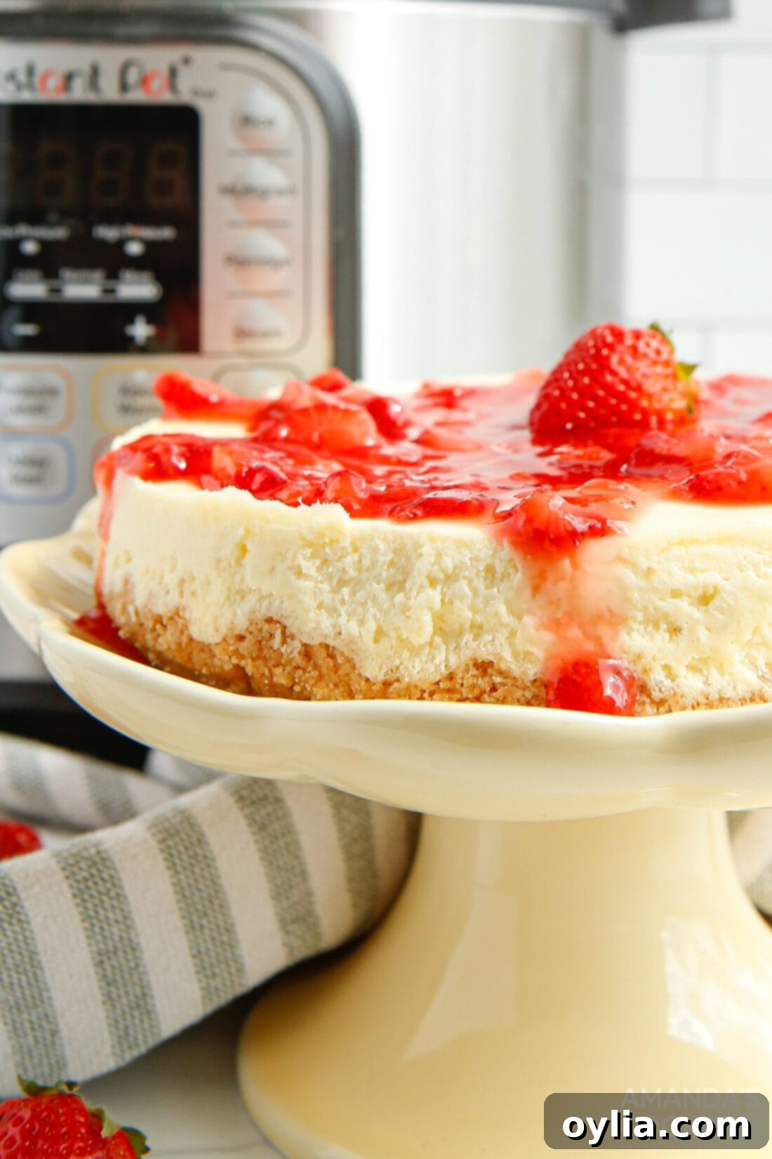 A whole Instant Pot Strawberry Cheesecake on a serving plate, topped generously with fresh strawberry sauce.