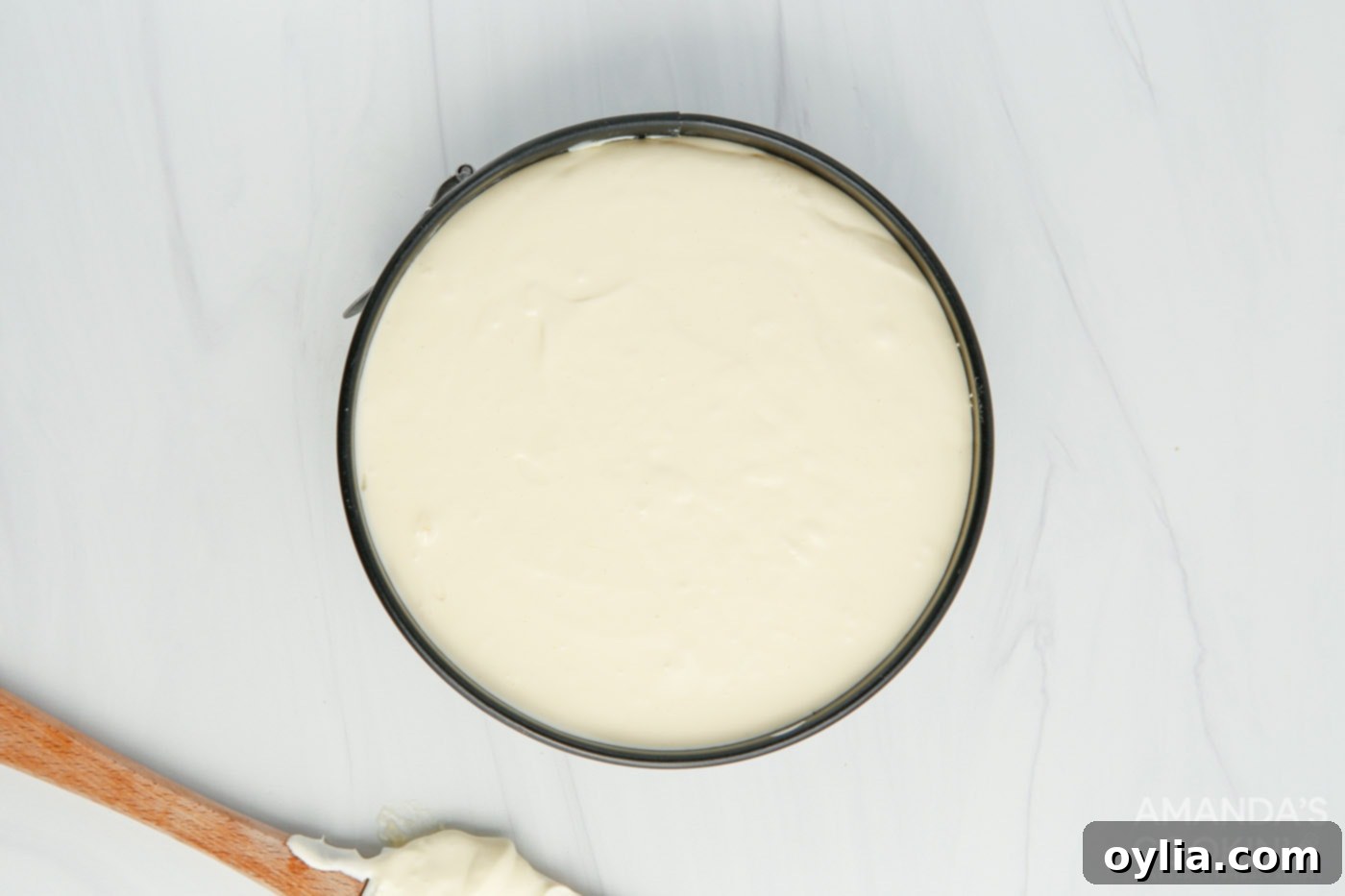 Smooth cheesecake filling poured into a graham cracker crust within a springform pan.