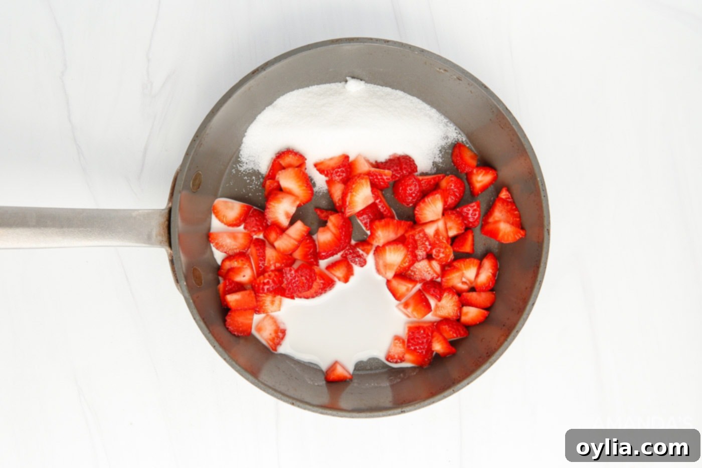 Diced strawberries with sugar and cornstarch in a bowl, before cooking into a sauce.