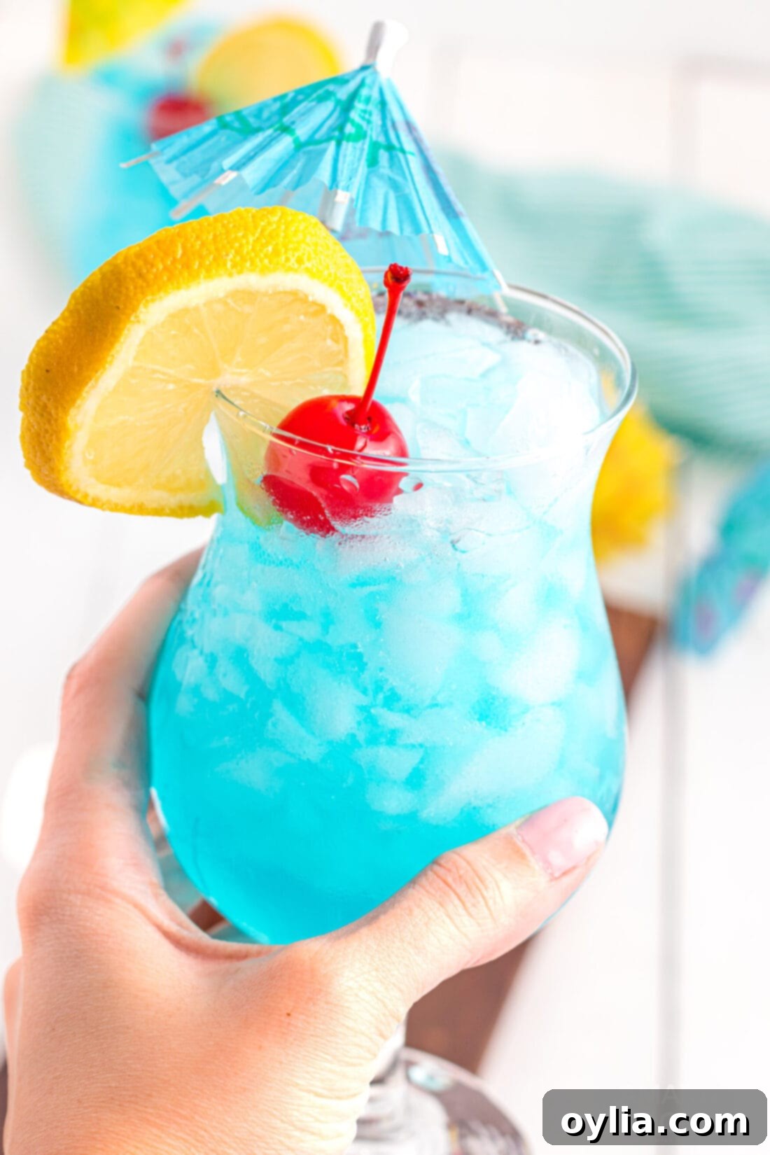 holding a Blue Lagoon Cocktail, showing its vibrant blue color