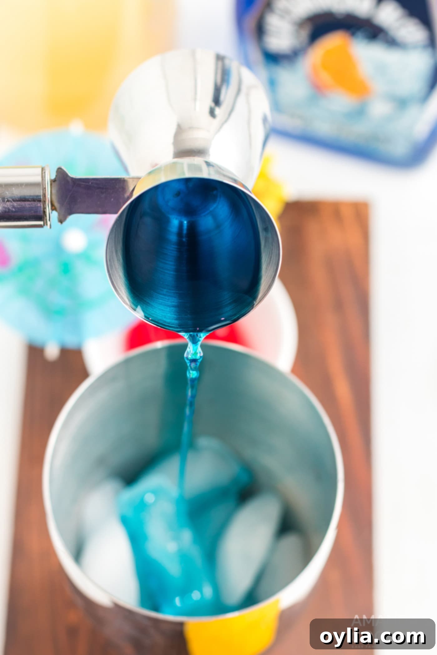 pouring blue Curacao into cocktail shaker with ice