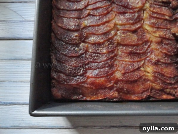 An overhead shot of an entire Dutch apple snack cake, beautifully arranged with apple slices and a golden-brown cinnamon sugar topping, suggesting its readiness to be served.