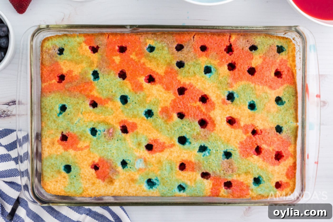 Drizzling red and blue jello liquid over a white poke cake