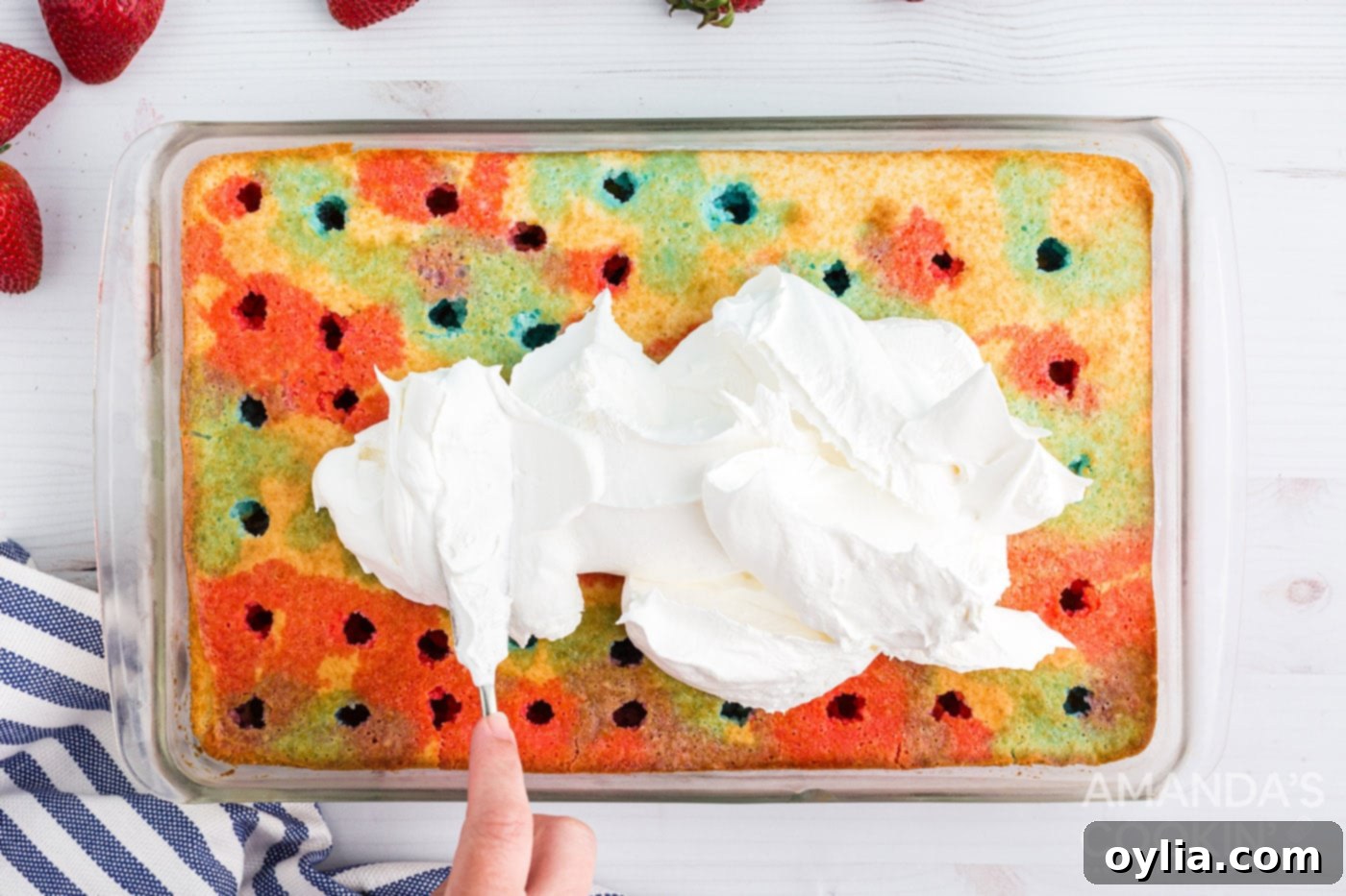 Spreading cool whip over the top of the cooled poke cake