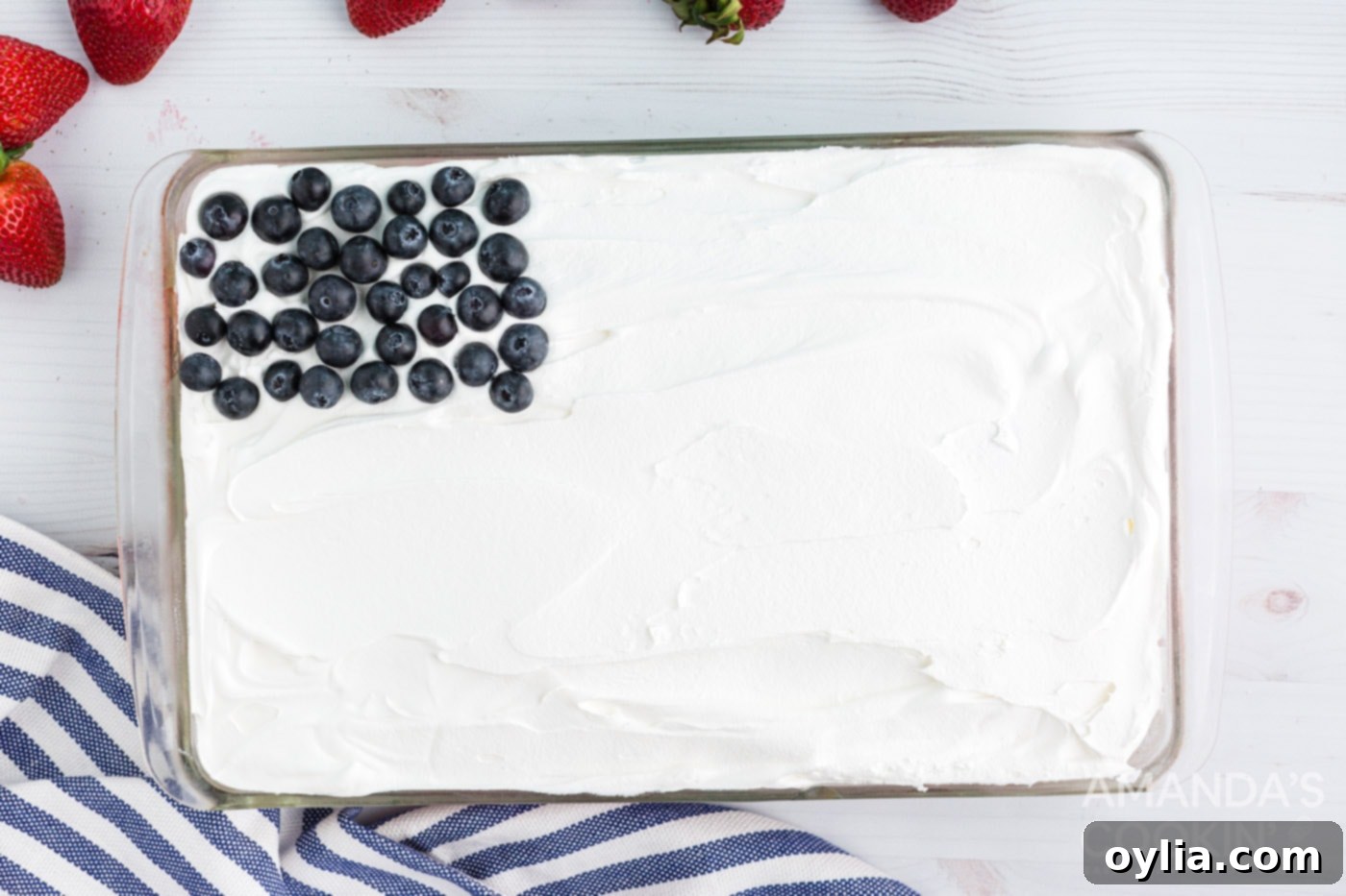 Blueberries arranged in the top left corner of the poke cake