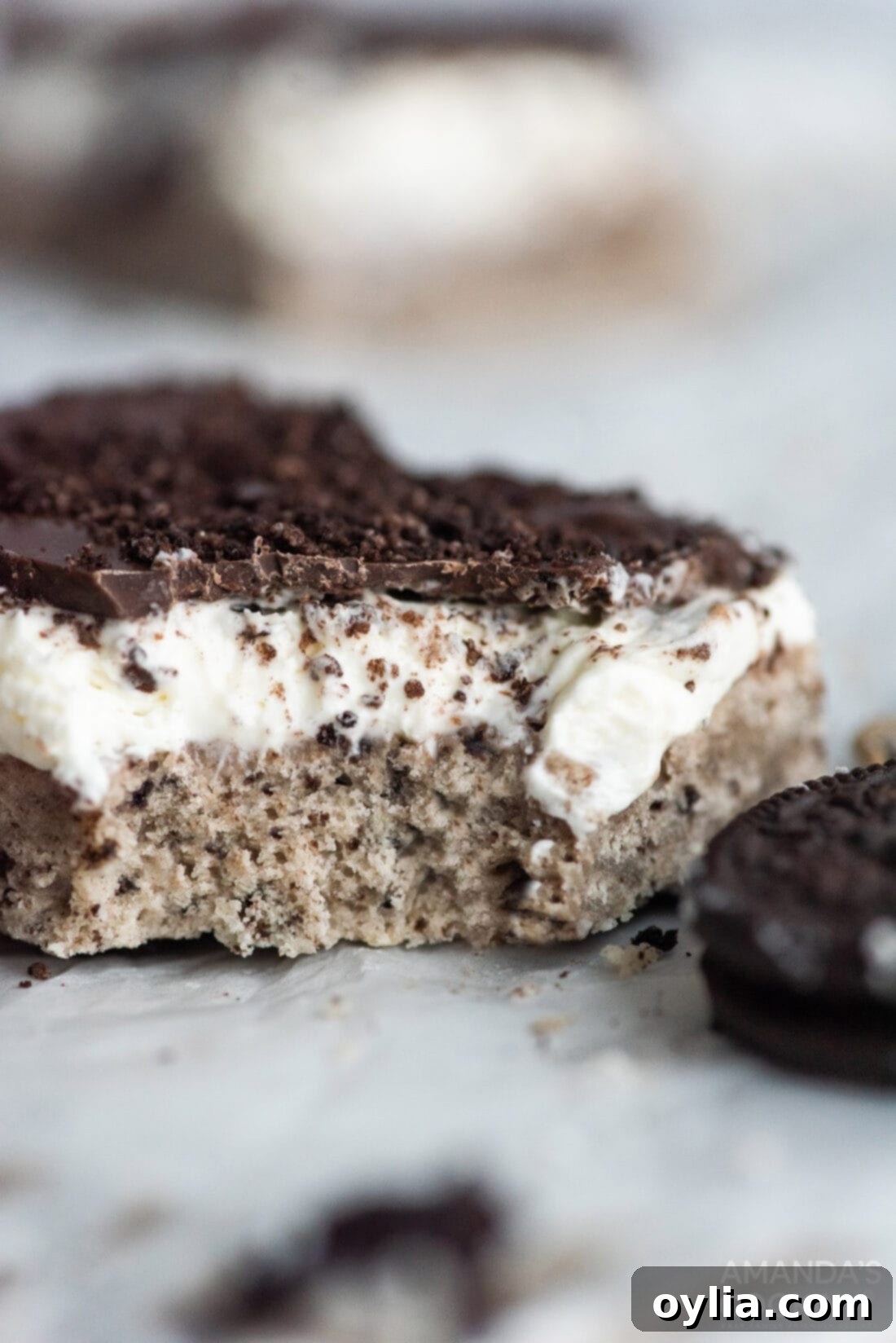 A perfectly cut Oreo cheesecake bar with a bite taken out, revealing the creamy layers and chocolate topping.