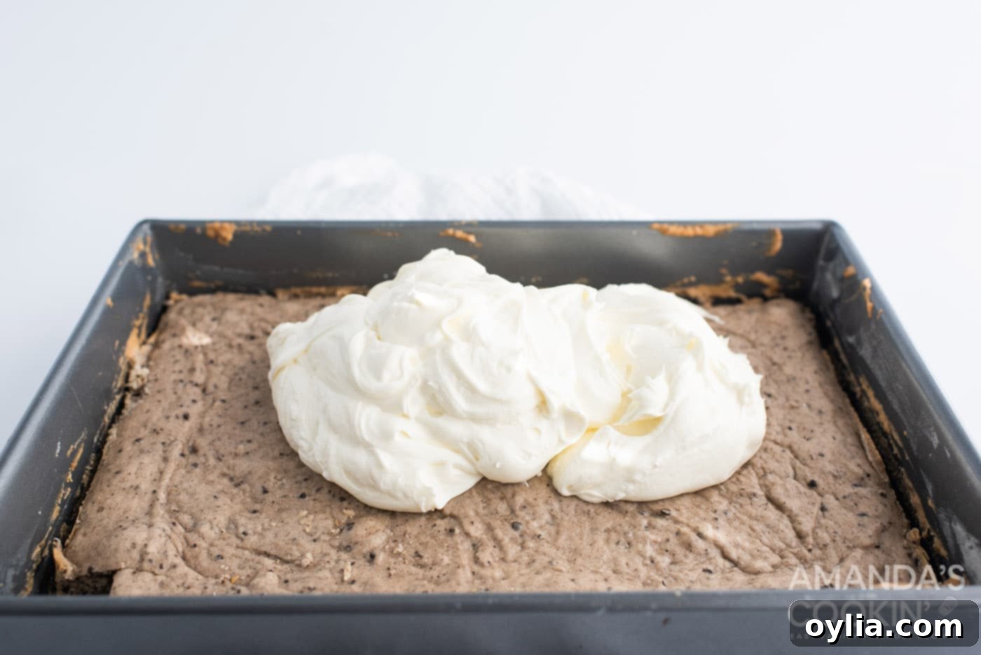 A pristine layer of creamy cheesecake spread over the baked Oreo cake base in a baking pan.
