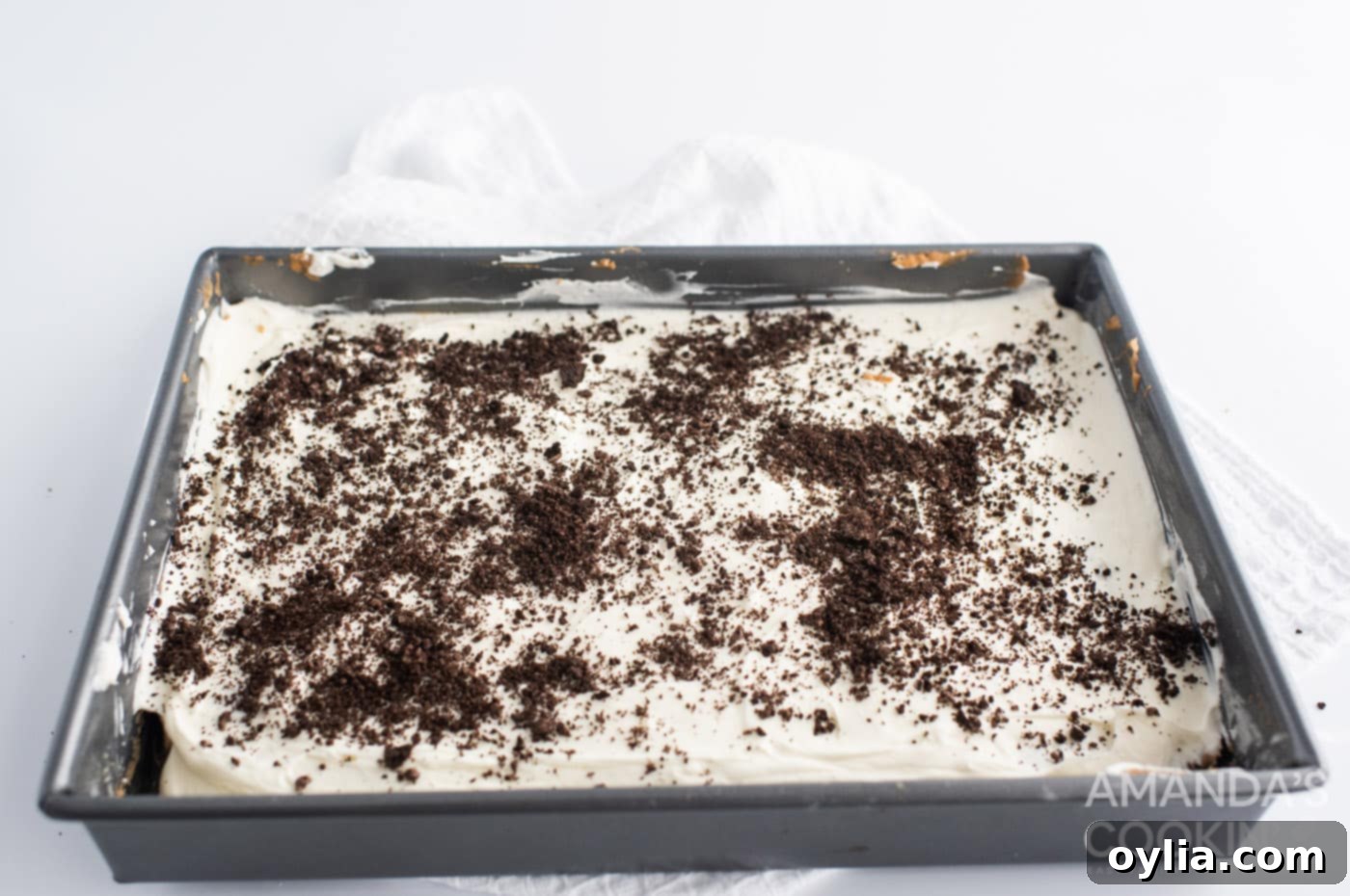 Oreo cheesecake bars with a generous sprinkling of Oreo crumbles on top, before the final chocolate layer.
